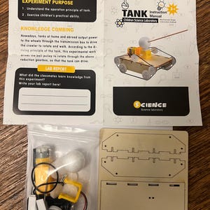 May include: A children's science laboratory kit with a tank model. The kit includes a wooden base, a bag of components, and an instruction manual. The manual explains the tank's operation principle. The kit is designed for children aged 3+.