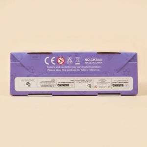 Peut inclure: Une bo&icirc;te violette avec du texte et des symboles blancs. Le texte comprend "CE", "NO.CH2041" et "MADE IN CHINA". La bo&icirc;te contient &eacute;galement des avertissements et des instructions imprim&eacute;s. La bo&icirc;te est sur un fond beige clair.