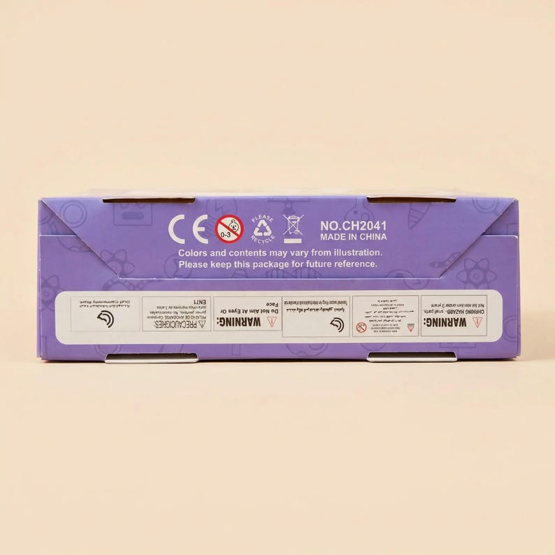 Peut inclure: Une bo&icirc;te violette avec du texte et des symboles blancs. Le texte comprend "CE", "NO.CH2041" et "MADE IN CHINA". La bo&icirc;te contient &eacute;galement des avertissements et des instructions imprim&eacute;s. La bo&icirc;te est sur un fond beige clair.