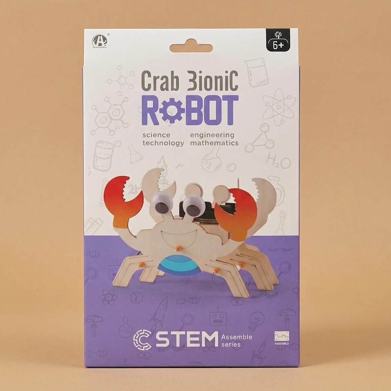 Peut inclure: Un kit de la s&eacute;rie STEM avec un robot bionique crabe en bois. La bo&icirc;te porte l'inscription "Crab Bionic Robot" avec les mots "science, technologie, ing&eacute;nierie, math&eacute;matiques". Le crabe a des pinces rouges et oranges et des yeux globuleux.