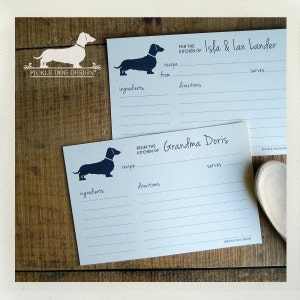 May include: Recipe cards with a dachshund silhouette. One card reads "For the kitchen of Isla & Ian Lander" and the other reads "From the kitchen of Grandma Doris". The cards have spaces for ingredients, directions, and servings.