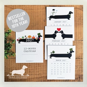 May include: A 2027 12-month calendar featuring illustrations of black dachshunds. The cover shows a dachshund with seasonal icons and the text 2027 12-MONTH CALENDAR. Individual pages display monthly grids with dachshunds wearing hats or scarves.