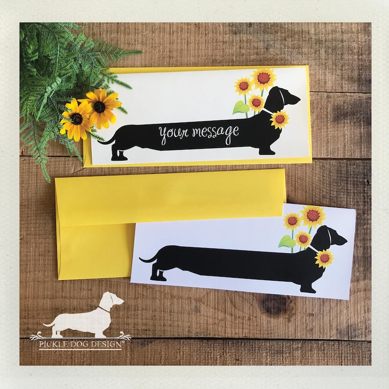 May include: Greeting cards featuring a black dachshund silhouette with sunflowers. The cards have the text "your message" and come with yellow envelopes. The design includes a logo of a dachshund.