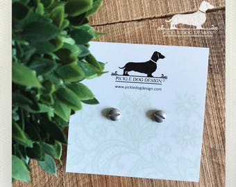 May include: A pair of silver screw-shaped stud earrings on a card with a dachshund logo. The card is on a wooden surface with green foliage in the background. The card reads "Pickle Dog Design" and the website address.