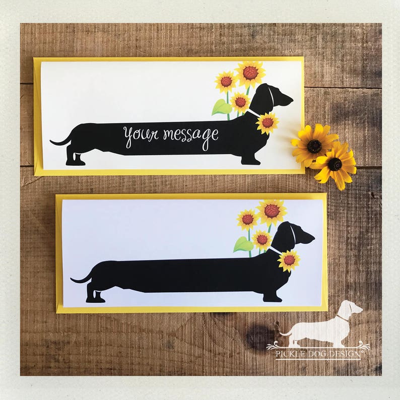 May include: Two greeting cards with a black dachshund silhouette adorned with sunflowers. The cards have a white background with the text "your message" and a yellow border. A few sunflowers are placed on the right side of the cards.