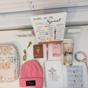 Peut inclure: Divers articles de foi, dont une couverture de Bible &agrave; motifs floraux, un bonnet rose avec le texte "Chosen", un carnet avec une illustration de croix et un gobelet de voyage avec le mot "Jesus". Comprend &eacute;galement un bracelet de perles et un petit calendrier.