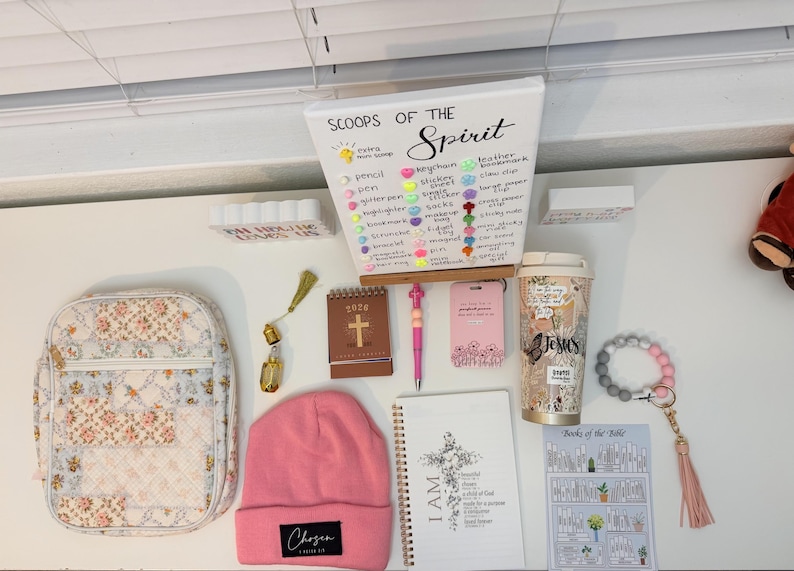 Peut inclure: Divers articles de foi, dont une couverture de Bible &agrave; motifs floraux, un bonnet rose avec le texte "Chosen", un carnet avec une illustration de croix et un gobelet de voyage avec le mot "Jesus". Comprend &eacute;galement un bracelet de perles et un petit calendrier.