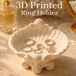Könnte beinhalten: Ein eleganter, 3D-gedruckter Ringhalter in Muschelform. Der cremefarbene Halter zeigt mehrere goldene Ringe. Der Text auf dem Bild lautet "Elegant 3D Printed Ring Holder."