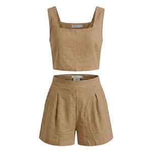 May include: A two-piece linen set in a neutral tan color. The set includes a square-neck crop top and high-waisted shorts with pleats. The fabric appears to be lightweight and suitable for warm weather.
