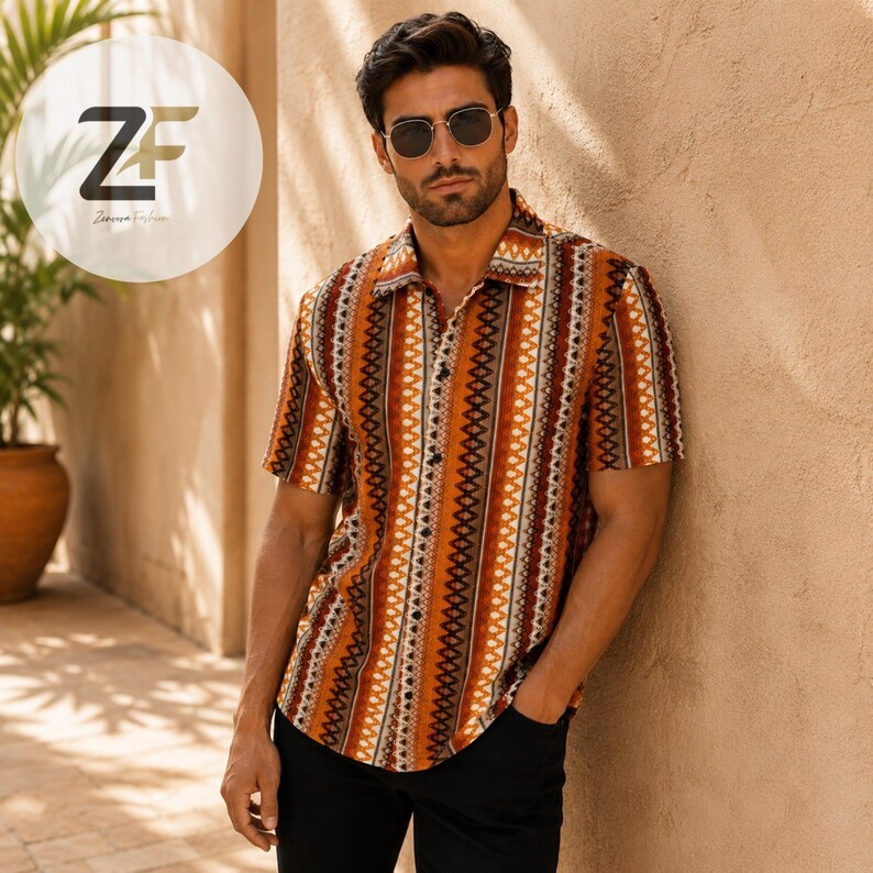 May include: A short-sleeved button-down shirt with a vertical striped pattern in shades of brown, orange, and white. The shirt has a classic collar and is worn with black pants. The image features a man wearing sunglasses.
