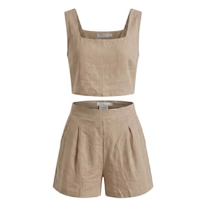 May include: A two-piece beige linen outfit. The set includes a square-neck crop top and high-waisted shorts with pleats. The fabric has a slightly textured appearance.
