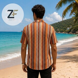 May include: Short-sleeved button-down shirt with a vertical geometric pattern in shades of orange, brown, and cream. The shirt is worn on a beach with a tropical background. The logo "ZF Zaroon Fashion" is in the upper left corner.