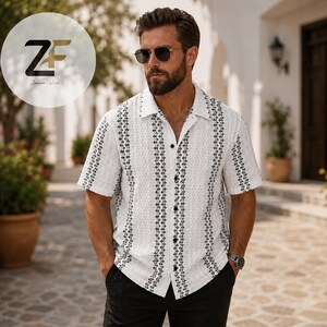 May include: White short-sleeve shirt with a textured pattern and black vertical stripes. The shirt has a classic collar and button-down front. The shirt is paired with black pants. The ZF logo is in the upper left corner.