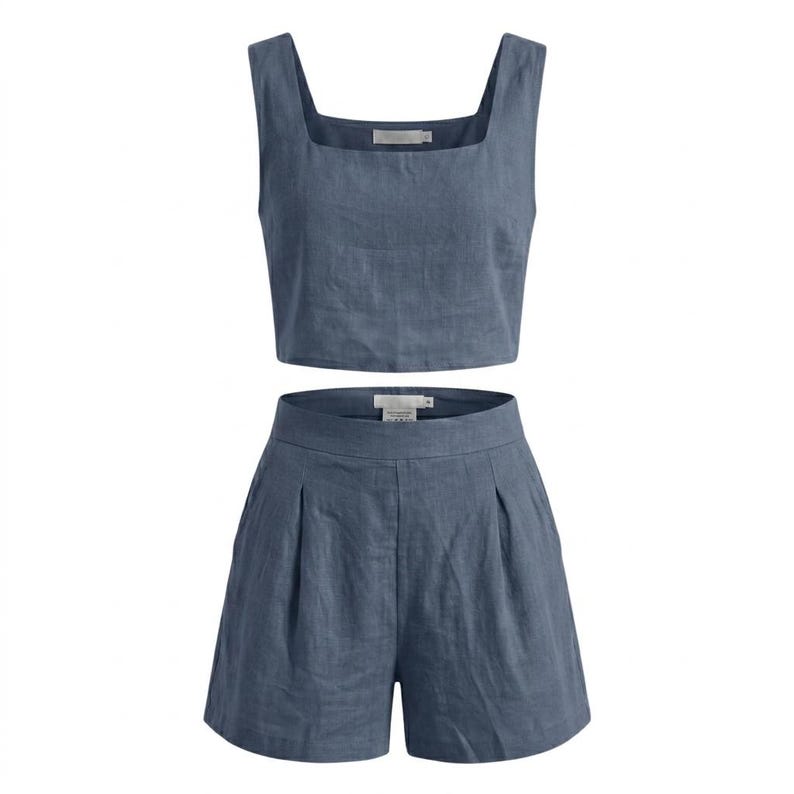 May include: A two-piece set of women's clothing in a dusty blue color. The set includes a crop top with a square neckline and wide straps, and high-waisted shorts with pleats. The fabric appears to be linen or a similar lightweight material.