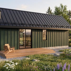 Op de afbeelding: Een kleine hut met donkergroene verticale gevelbekleding, een zwart metalen dak en een houten terras. De structuur is voorzien van een glazen schuifdeur, een enkel raam en een schoorsteenpijp. Een houten stoel staat op het terras.