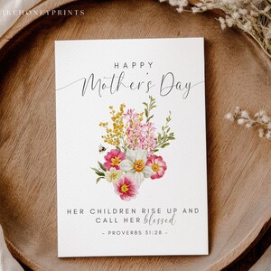 May include: A white Mother's Day card with floral illustrations and the text "Happy Mother's Day." The card features a bouquet of pink, yellow, and white flowers. The text "Her children rise up and call her blessed" is also included.