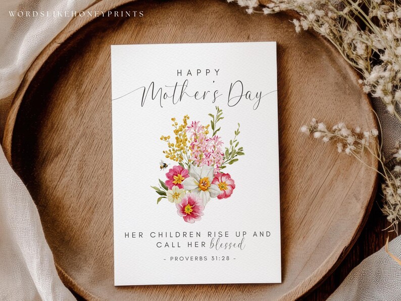 May include: A white Mother's Day card with floral illustrations and the text "Happy Mother's Day." The card features a bouquet of pink, yellow, and white flowers. The text "Her children rise up and call her blessed" is also included.