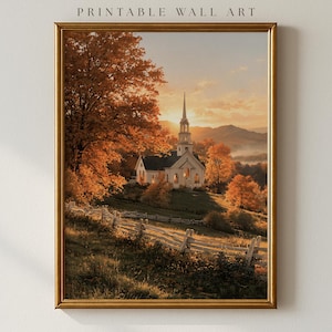 May include: A framed wall art print featuring a white church with a steeple set in a landscape of autumn trees with orange foliage. A wooden split-rail fence runs across the foreground of the grassy hill under a golden sunset sky.