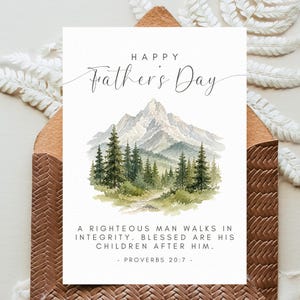 May include: Father's Day greeting card with a watercolor mountain and forest scene. The card reads "Happy Father's Day" and includes a Bible verse. The card is inside a brown envelope.