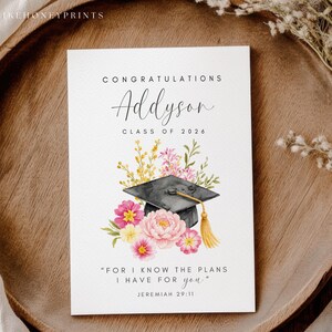Puede incluir: Tarjeta de graduaci&oacute;n con el nombre "Addyson" y el a&ntilde;o "2026". La tarjeta presenta una ilustraci&oacute;n en acuarela de un birrete, flores y la cita "Porque yo s&eacute; los planes que tengo para vosotros" de Jerem&iacute;as 29:11.
