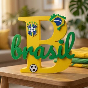 May include: A large yellow letter B featuring the green cursive word brasil across the front. The letter includes a blue and yellow map of Brazil, a CBF soccer crest, and a small black and white soccer ball graphic attached to the surface.