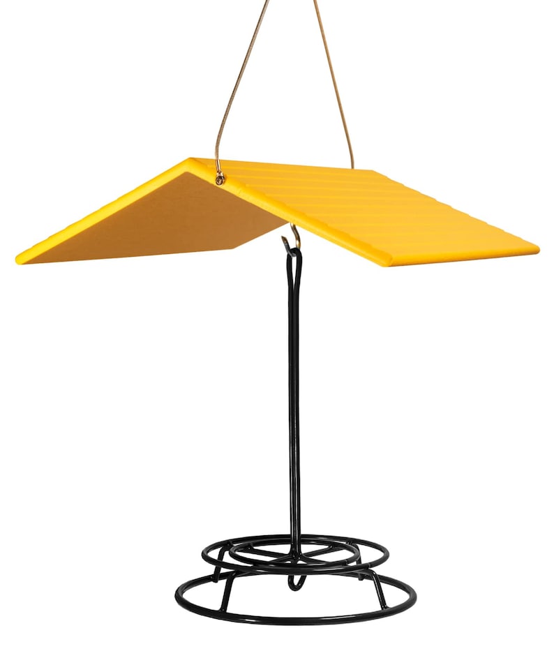 May include: Yellow bird feeder with a black metal base and a yellow roof. The feeder hangs from a wire loop.