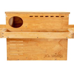 May include: A wooden birdhouse with two pull-out trays. The birdhouse has a small opening for birds to enter and a J.C. Wildlife logo on the front.