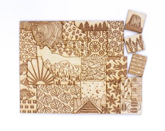 May include: A wooden puzzle featuring various nature-themed designs, including a mountain range, a sun, a forest, and a geometric pattern. The puzzle pieces are arranged in a rectangular shape, resembling a map or a landscape.