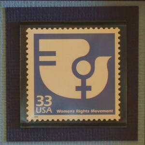 Op de afbeelding: Een blauwe en witte postzegel met de tekst "33 USA" en "Women's Rights Movement". De zegel toont een gestileerd symbool van het vrouwelijke geslacht.