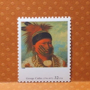May include: A 1998 United States postage stamp depicting a portrait of a Native American man with red and white face paint. The stamp is titled "George Catlin (1796-1872)" and has a value of 32 cents.