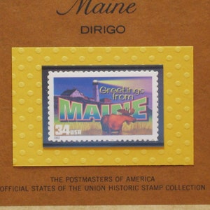 May include: A vintage postage stamp featuring a moose and a lighthouse with the text "Greetings from Maine". The stamp is framed in a yellow background with a polka dot pattern.