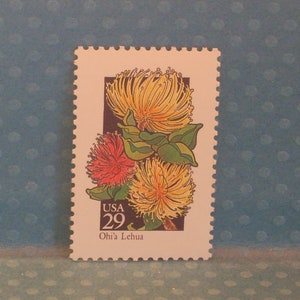Puede incluir: Un sello postal estadounidense vintage con una flor amarilla y roja con hojas verdes. El sello está etiquetado como "USA 29" y "Ohi'a Lehua".