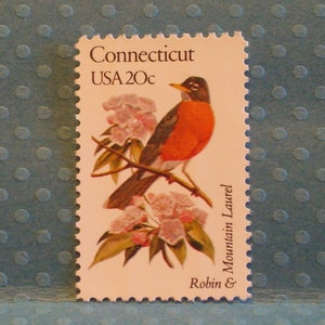 May include: A vintage US postage stamp featuring a red robin perched on a branch of mountain laurel flowers. The stamp is from Connecticut and has a value of 20 cents.