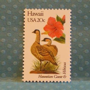 May include: A postage stamp from Hawaii, USA, featuring two Hawaiian geese and a vibrant red hibiscus flower. The stamp is marked "Hawaii USA 20c" and includes the text "Hawaiian Goose & Hibiscus."