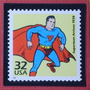 May include: A vintage-style 32 cent US postage stamp featuring Superman in a red cape and blue suit, flying with the text "Superman Arrives 1938" and the year "1998" printed on the stamp.