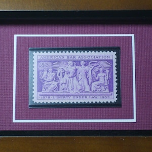 May include: A framed purple stamp with the text "AMERICAN BAR ASSOCIATION" and "U.S. POSTAGE 3&cent; 1978 LIBERTY UNDER LAW 1953".