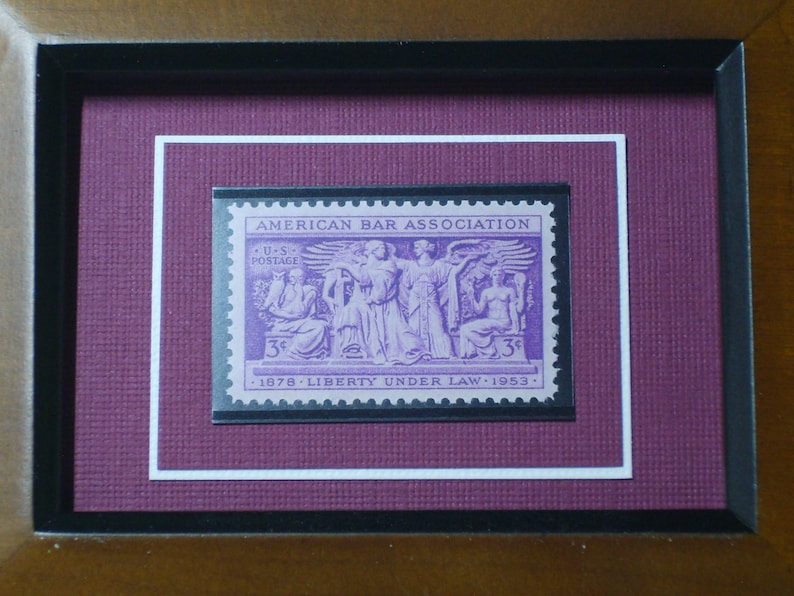 May include: A framed purple stamp with the text "AMERICAN BAR ASSOCIATION" and "U.S. POSTAGE 3&cent; 1978 LIBERTY UNDER LAW 1953".