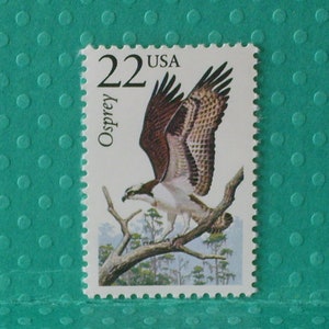 May include: A 22 cent USA postage stamp featuring an Osprey bird in flight with the word "Osprey" printed vertically on the left side of the stamp.