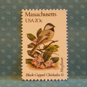 May include: A vintage postage stamp from Massachusetts, USA, featuring a Black-Capped Chickadee perched on a flowering branch. The stamp has a 20-cent value and includes the text "Massachusetts", "USA 20c", "Black-Capped Chickadee & Mayflower".
