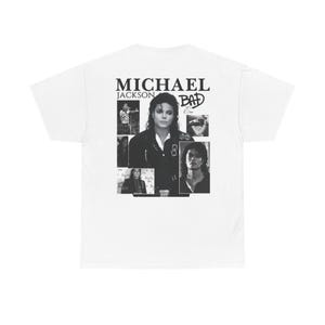 May include: White t-shirt featuring a black and white graphic of Michael Jackson. The design includes the text "MICHAEL JACKSON" above the word "BAD" and several black and white images of the artist.