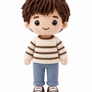 May include: A handmade crochet doll featuring a person with short brown yarn hair, black plastic eyes, and a stitched smile. The doll wears a cream-colored long-sleeve sweater with horizontal brown stripes, blue cuffed pants, and brown and white sneakers.