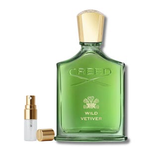 May include: A green glass perfume bottle with a gold cap and the word "CREED" printed on the front. The bottle is labeled "WILD VETIVER". A small spray bottle and cap are next to the perfume bottle.
