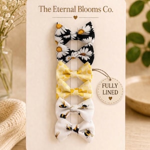 May include: A set of four fabric hair bows in a variety of patterns, including daisies, yellow honeycomb, and bees. The bows are attached to a cream-colored card with the text "The Eternal Blooms Co." and a "FULLY LINED" tag.