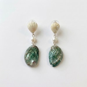 May include: A pair of drop earrings featuring a small white ribbed seashell at the top, a single white spherical bead in the center, and a larger iridescent green abalone shell at the bottom, all connected by thin silver-toned metal links.