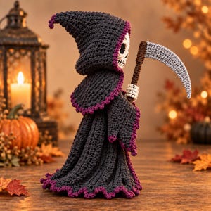 May include: A crocheted grim reaper figure wearing a dark charcoal hooded cloak with purple scalloped trim. The figure has a white skull face and holds a brown-handled scythe with a light gray blade. The construction is entirely yarn-based.