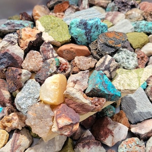Peut inclure: Un assortiment de pierres précieuses et de minéraux bruts. La collection comprend des pièces vertes, bleues, marron, grises et jaunes. Les pierres ont une texture naturelle et rugueuse, de tailles et formes variées, mettant en valeur leurs caractéristiques uniques.