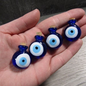 May include: Four small blue glass bottles with cork stoppers. Each bottle has a white and blue evil eye charm attached.