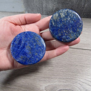 lapis lazuli thick large round crystal disks in hand with grey background