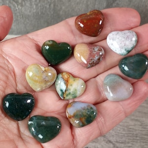moss agate 17 mm heart cabochons with puffy front in hand with grey background