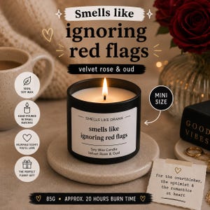 May include: A black candle with the text "Smells like ignoring red flags" and "Velvet Rose & Oud." The candle is labelled "Smells Like Drama" and is a mini size. The candle is 85g and has an approximate 20-hour burn time.